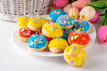 Fototapeta na wymiar Homemade Italian Easter cookies with colorful sugar glaze and sprinkles, on white kitchen table background, decorated with Easter holiday decor and spring tulip flower bouquet 