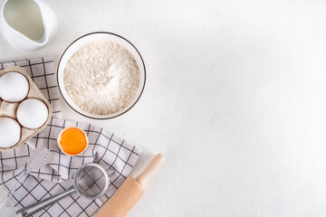 Empty space baking background with bakery ingredients - flour, milk, eggs, rolling pin. Simple pastry baking flat lay top view border