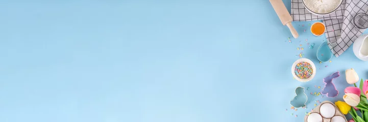 Afwasbaar fotobehang Easter baking background, ingredient for making Easter cookies, cakes, dessert with Easter chocolate eggs, sugar sprinkles, baking ingredients, flour, egg, milk, rolling pin, spring flowers top view © ricka_kinamoto