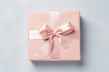 A soft pink gift box with a silky satin ribbon, beautifully tied in a bow, presented on a subtle light background - 715835086