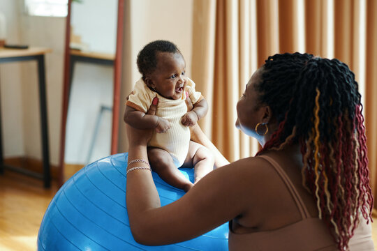 Mother placing baby in seated position on exercise ball