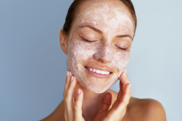 Self love. Skin care beauty portrait. Facial scrub, young happy woman with a freckles is applying...