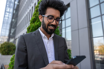 Fototapeta premium Bearded smiling handsome hindu businessman with a phone in hands