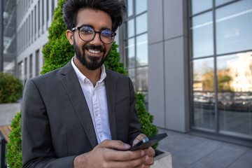 Bearded smiling handsome hindu businessman with a phone in hands