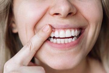 Cropped shot of a young caucasian blonde smiling woman applying mineralizing gel to teeth for...