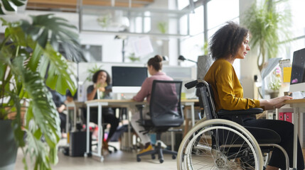 personne handicapée en fauteuil roulant travaillant sur son ordinateur dans un open space avec d'autres personnes valides 