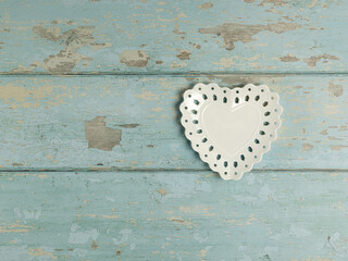 Heart shaped plate with hole decoration on vintage wooden background. Top view.