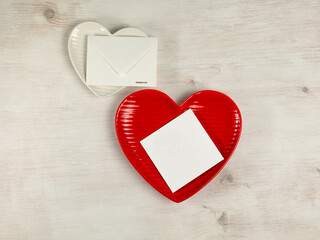 Heart shaped plates, paper card, envelope on white wooden background. Top view. - 715845047
