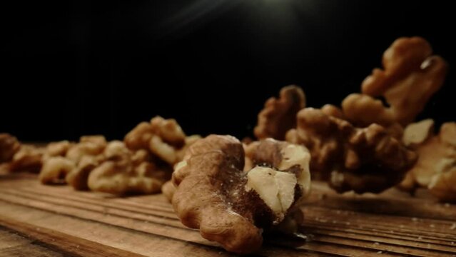 Close up shot of food ingredients on the wooden surface in studio. Many freshly roasted peeled walnuts scattered around and falling on the table.