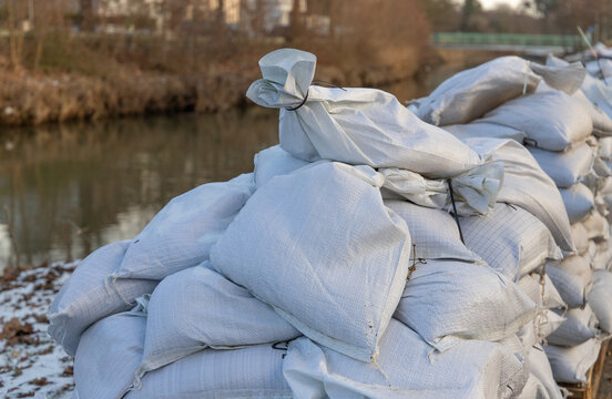 stack of filled sandbags near a river due to floodwater