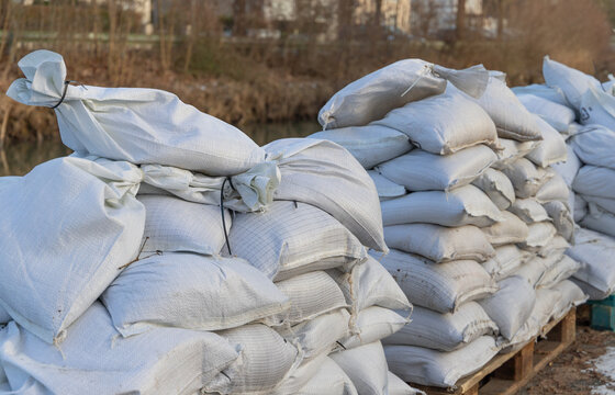 stack of filled sandbags near a river during floodwater