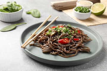 Tasty buckwheat noodles (soba) with chili pepper, onion and chopsticks on light table