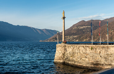 The old port with the statue of Madonnina in Luino, located on the coast of Lake Maggiore, Italy