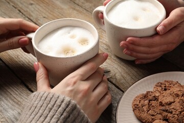 Women having coffee break at wooden table, closeup