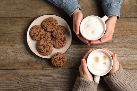 Women having coffee break at wooden table, top view