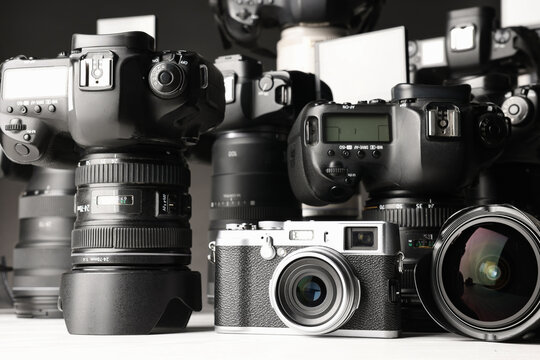 Modern cameras on white table, closeup. Professional photography equipment