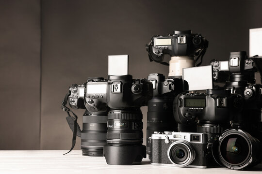 Modern cameras on white wooden table against dark background