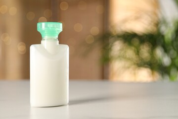 Mini bottle of cosmetic product on white table against blurred background. Space for text