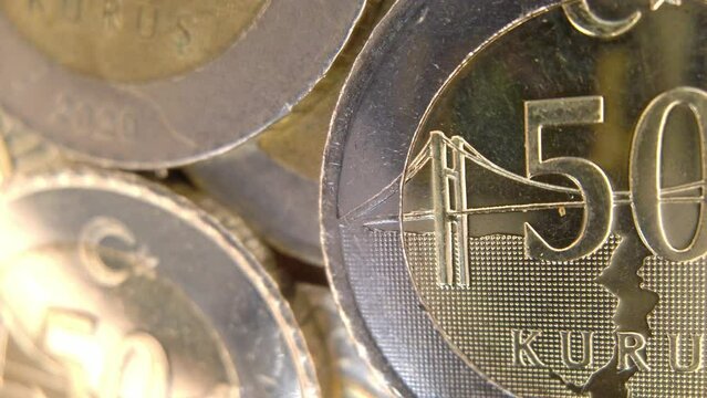 A macro shot of a 50 Kuruş coin with the camera panning from left to right, showing the fine lines and patterns of the currency. The coin is bimetallic, with a bronze center and a silver ring. 