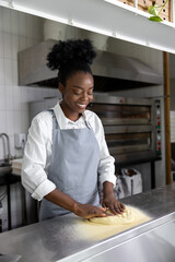 Fototapeta na wymiar African american young woman preparing pizza in pizzeria kitchen