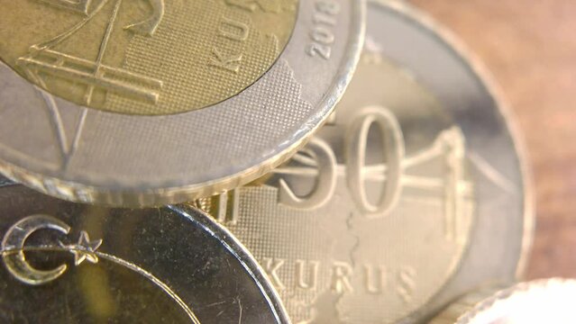 A macro shot of a 50 Kuruş coin with the camera panning from left to right, showing the fine lines and patterns of the currency. The coin is bimetallic, with a bronze center and a silver ring. 