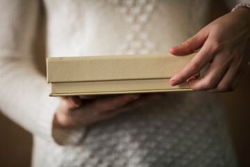 a woman opens a beige leather box for photo book. Woman hands holding and opening brown box....