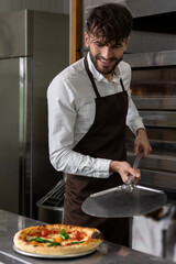 Smiling cooker preparing tasty pizza in pizzeria