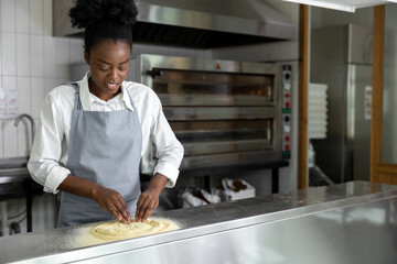 African american young woman preparing pizza in the kitchen