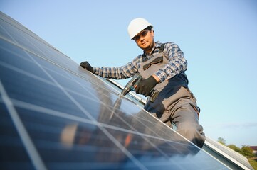 An Indian worker in uniform and with tools works on a solar panel farm
