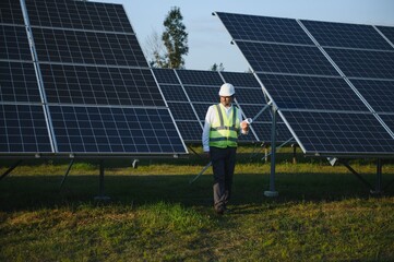 Industrial senior man engineer walking through solar panel field for examination