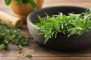 Bowl of fresh rosemary medicinal herbs. Twigs of thyme and mint on background. Healing herbs,...