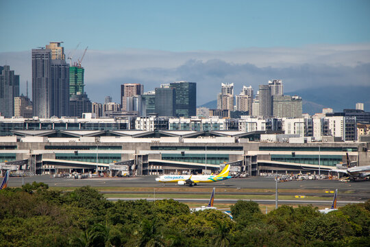 Aerial view of Cebu Pacific aircraft on taxiway and Terminal 3 at Ninoy Aquino International Airport, with the Manila skyline in the background - Manila, Philippines	