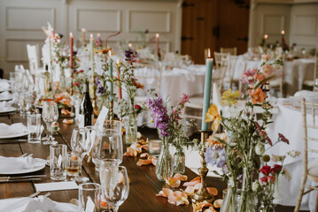 Wedding reception tables decorated with colourful flowers and candles and summery decor