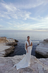 Fototapeta na wymiar beautiful bride in luxurious wedding dress posing on the beach in Cyprus