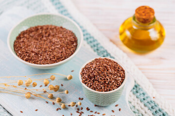 Brown linen seeds, flaxseed vegetable oil on white wooden background. Healthy super food