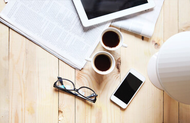 Black coffee with blank digital tablet and mobile phone, magazines and glasses on the table