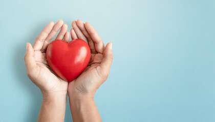 adult hands around red heart on light blue pastel background health care organ donation family life insurance world heart day world health day praying concept
