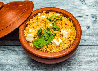 paneer biryani rice served in claypot dish isolated on wooden table top view of indian spicy food