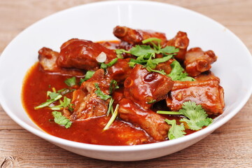 Chinese Red Soup Pork Ribs served on a white plate, a popular Chinese dish, made from sliced pork ribs and tomato sauce.