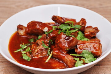 Chinese Red Soup Pork Ribs served on a white plate, a popular Chinese dish, made from sliced pork ribs and tomato sauce.