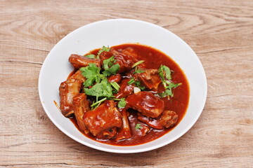 Chinese Red Soup Pork Ribs served on a white plate, a popular Chinese dish, made from sliced pork ribs and tomato sauce.