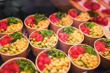 Colorful poke bowls, a Hawaiian raw fish salad, in eco-friendly containers.