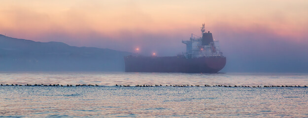 Container Ship in Burrard Inlet during foggy sunset. Vancouver - obrazy, fototapety, plakaty