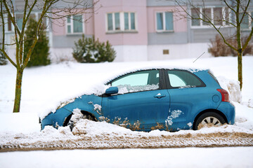 Snow covered car stuck at roadside after snow removal works. Stuck car in snowdrift. Snow removal...