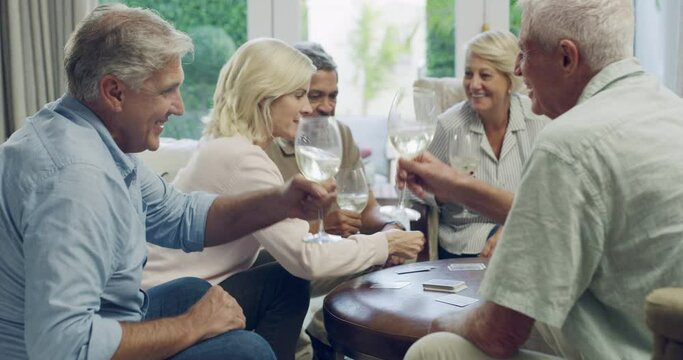 Mature friends in home, playing cards and wine with bonding, support and relax together in living room. Games, senior men and women in lounge with happiness, drinks and cheers on fun social weekend.