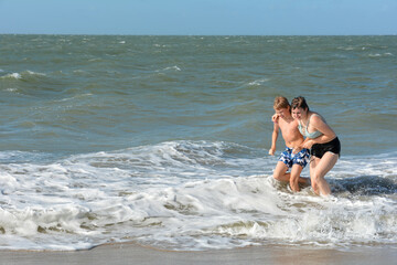 A boy and a teenage girl come out of the water from the sea
