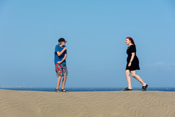 Two teenagers stand on a sand dune
