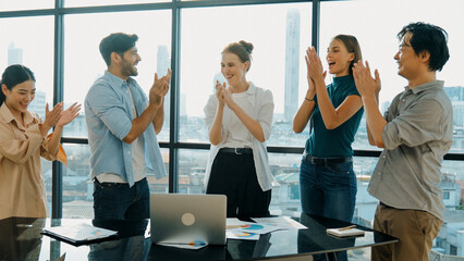 Professional business team clapping hand together with document scatter around at business meeting...