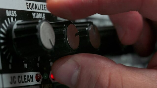 Man plug in jack and tuning volume knob on guitar amplifier. 4k video footage UHD 3840x2160