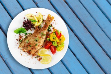 Fried tasty fish dish with vegetable served on plate
